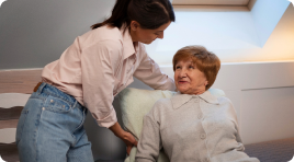 A woman providing care to an elderly woman who needs assistance with daily living activities