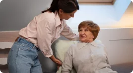 A woman providing care to an elderly woman who needs assistance with daily living activities
