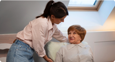 A woman providing care to an elderly woman who needs assistance with daily living activities
